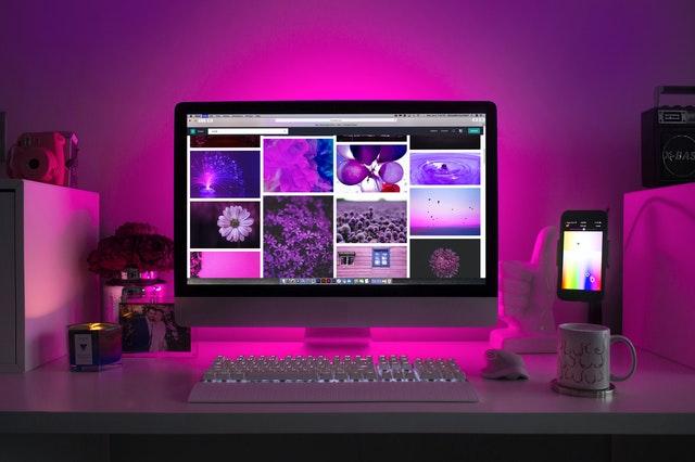 This computer screen in a purple lit room links to a product page that Vicki Nemeth wrote about a work-from-home IT package.